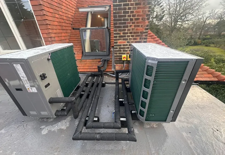 The two Samsung units side by side on the flat roof, flow and return in insulated pipe between them.
