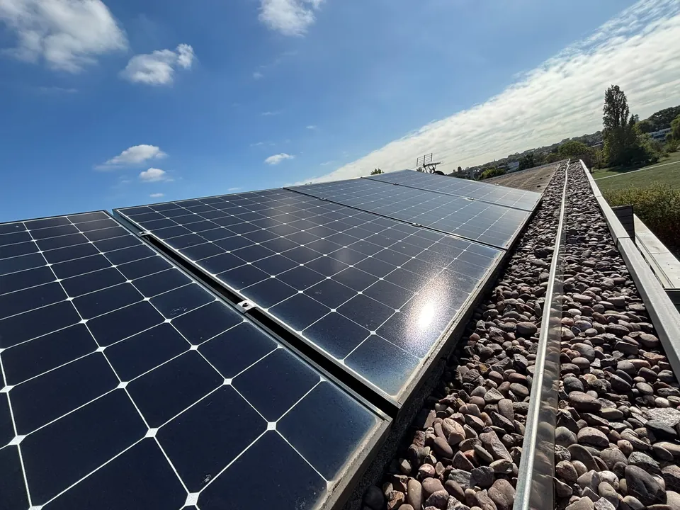 The array on ballasted frames, with the access strip left along the parapet.