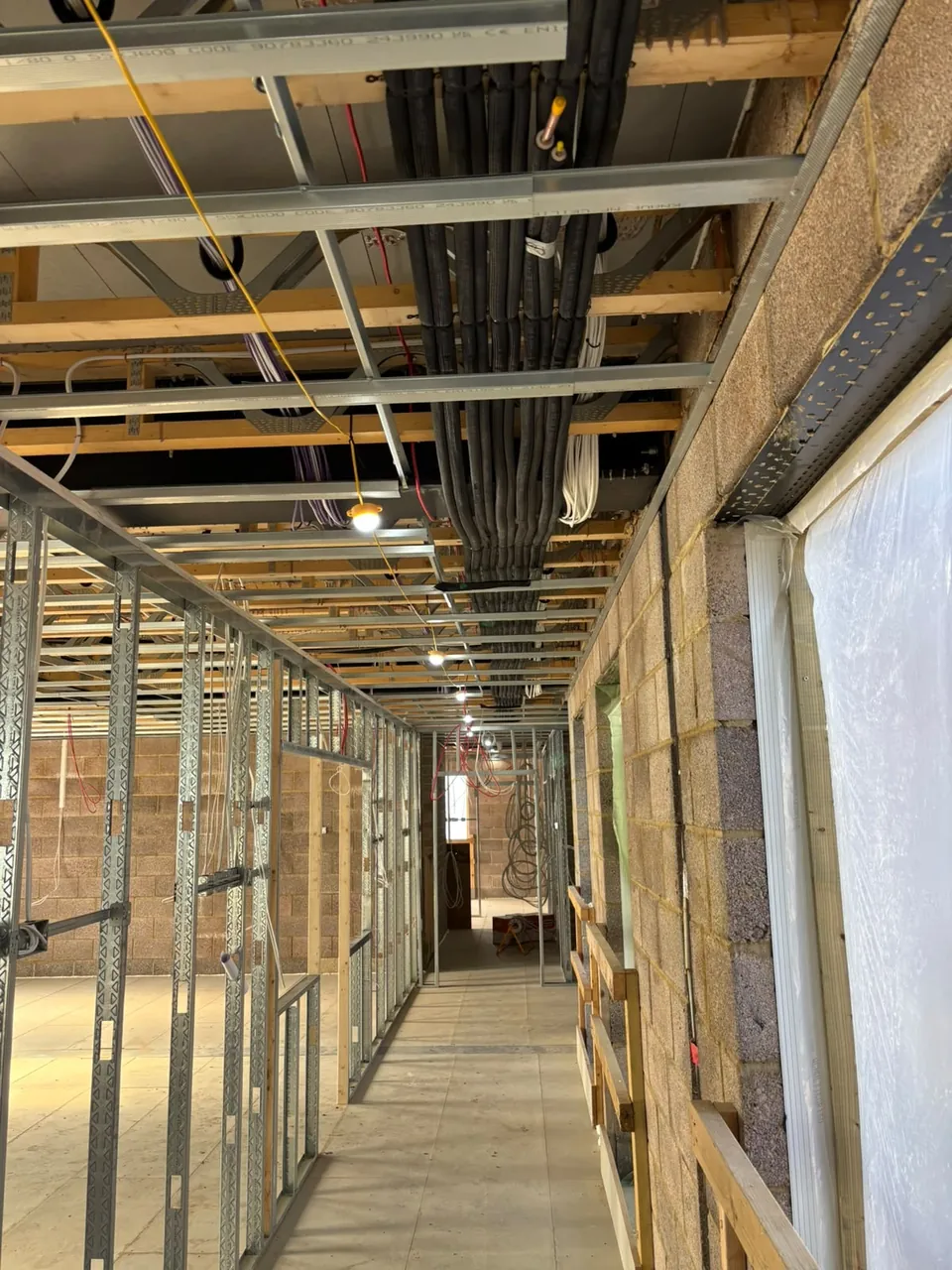 Insulated refrigerant pipework in the ceiling void above the corridor, under the joists.