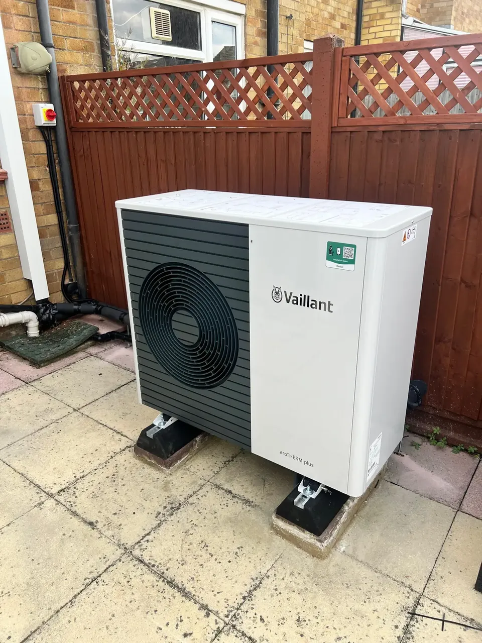 The aroTHERM plus on rubber blocks on the existing patio, against the rear fence.