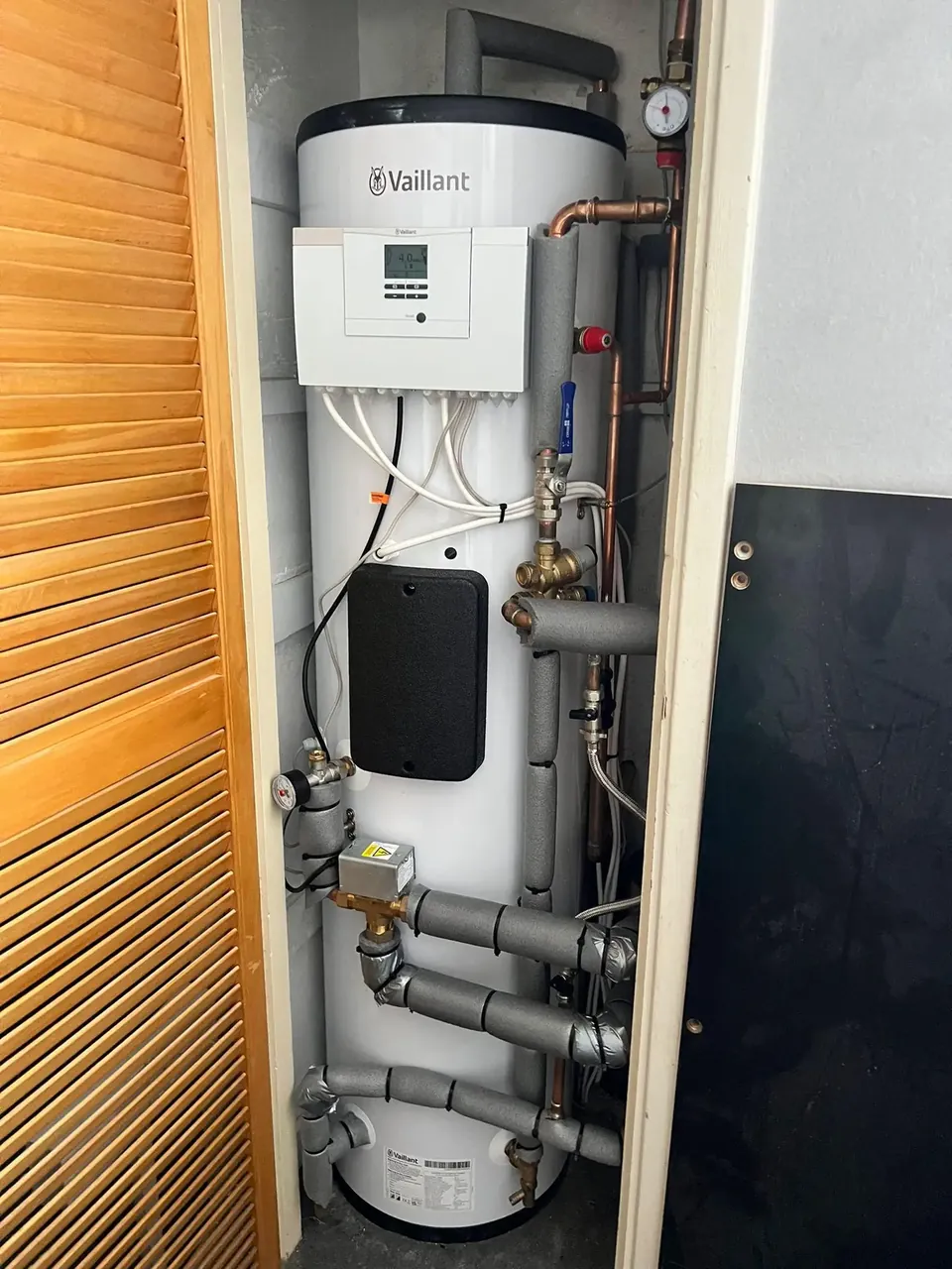 The new cylinder and controller in the cupboard the old hot water came from.