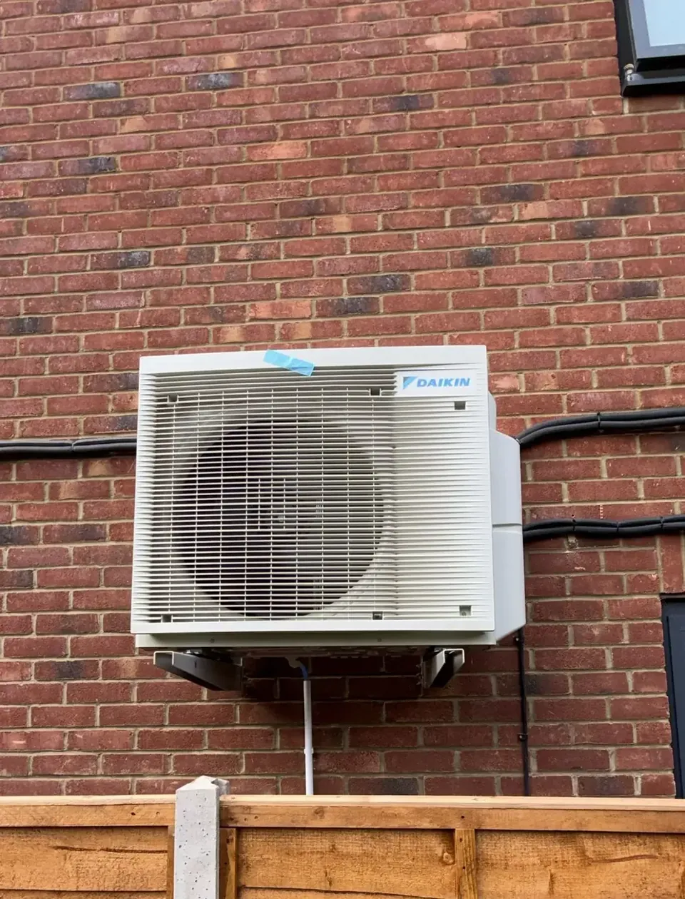 The Daikin outdoor unit on wall brackets, with the refrigerant lines in trunking.