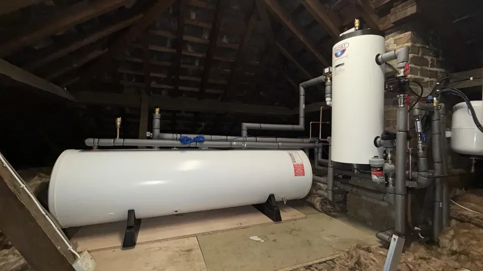 The 300-litre cylinder lying horizontally in the loft, with the buffer beside it.