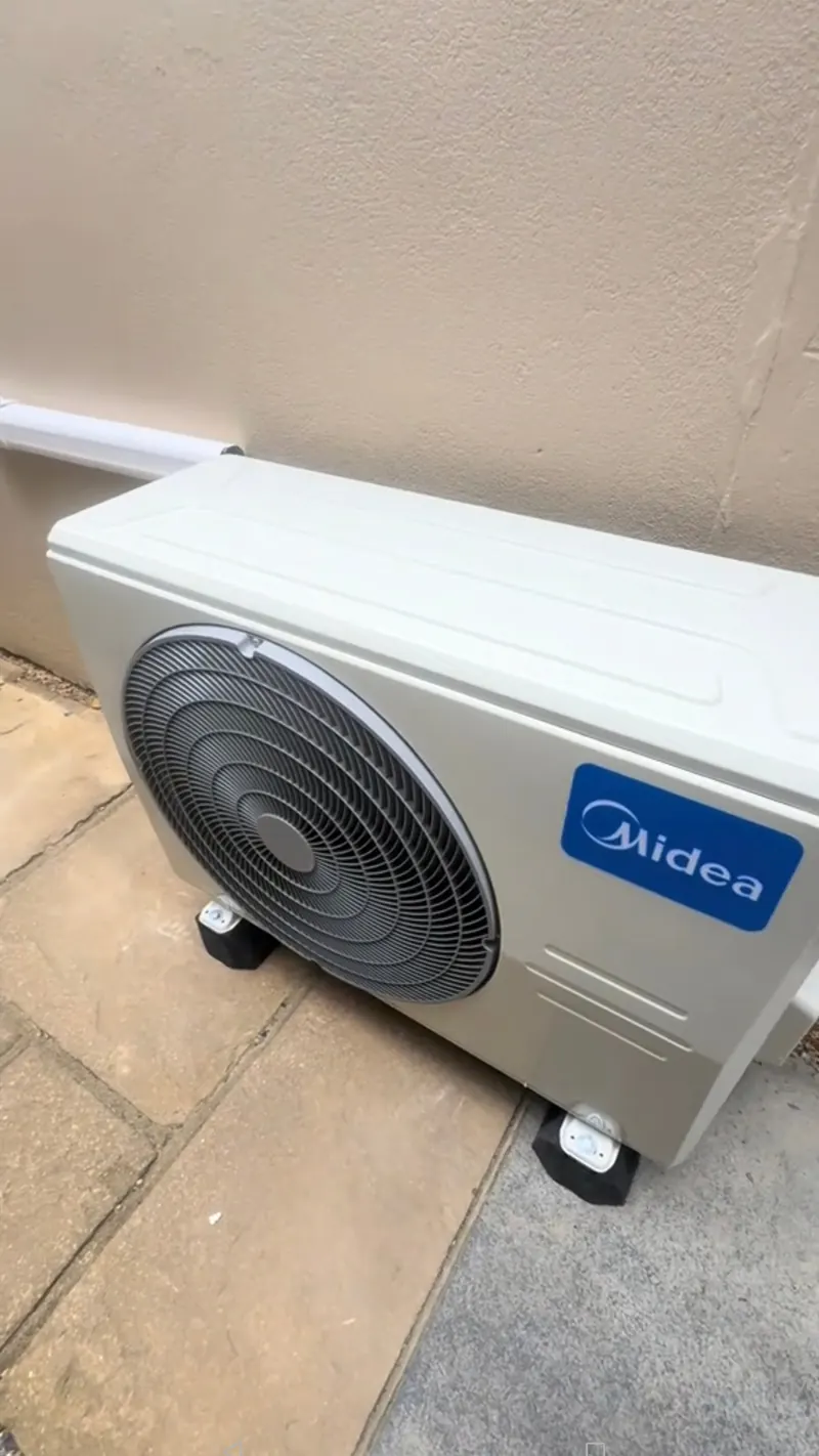 Finished air conditioning outdoor unit on paving slabs beside a north London house wall