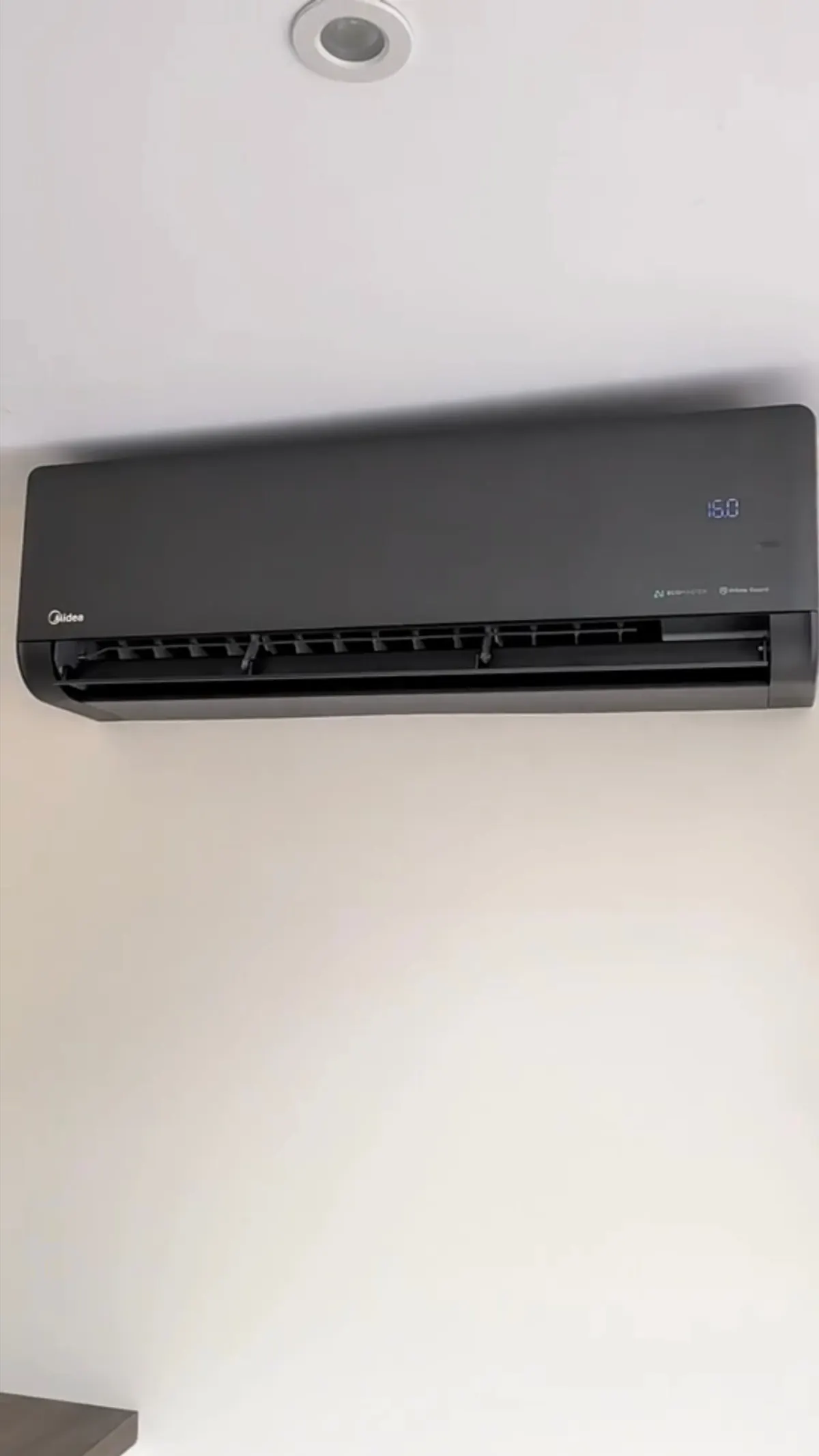 Wall-mounted indoor air conditioning unit showing its set temperature on the display in a London bedroom