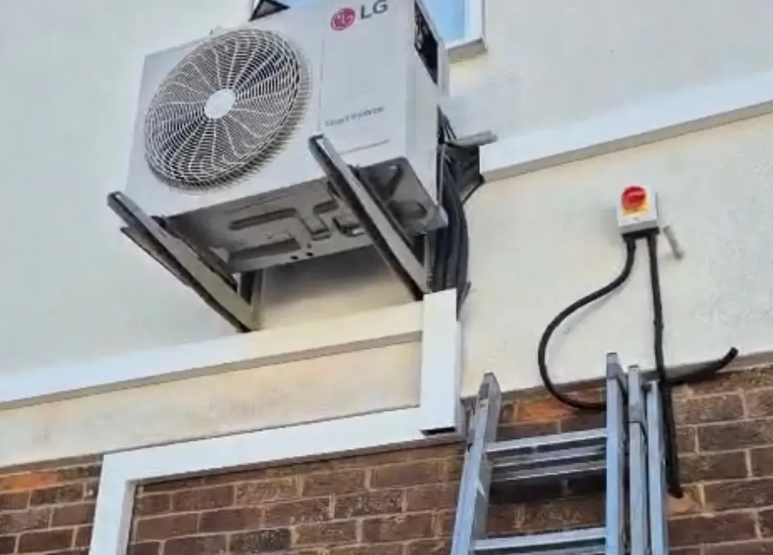 Air conditioning outdoor unit mounted on brackets above a London brick wall
